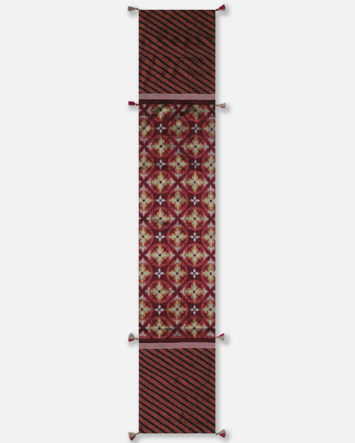 Full-length view of the Hearth runner showing the transition from maroon floral-geometric ikat to black diagonal stripes on rust-red.