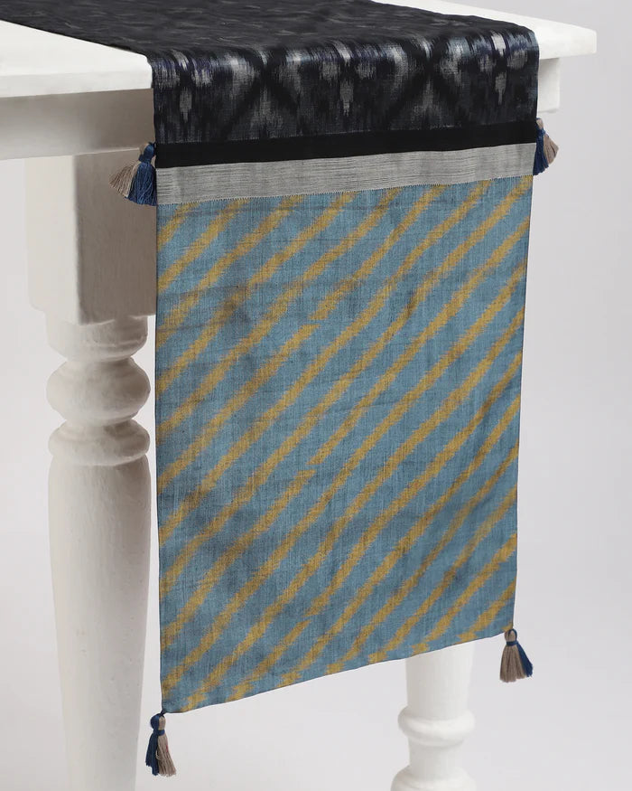 Indigo, black and ochre ikat runner with tassels, draped on a table