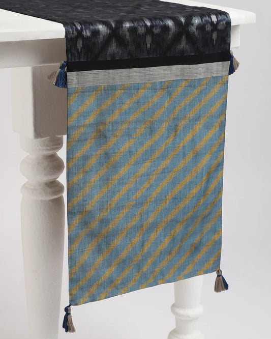 Indigo, black and ochre ikat runner with tassels, draped on a table