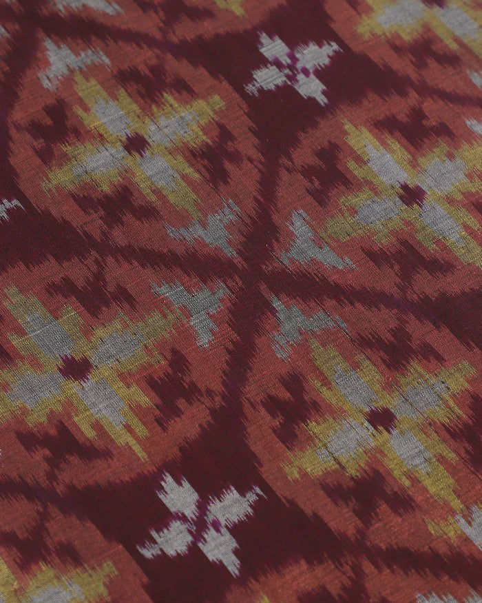 Macro view of the Hearth runner center: gold and silver-grey floral-geometric ikat motifs on a deep burgundy silk field.