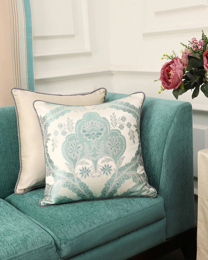 A Mint Silk Gyasar pillow styled on a deep teal sofa, demonstrating its tonal compatibility with modern luxury interiors.