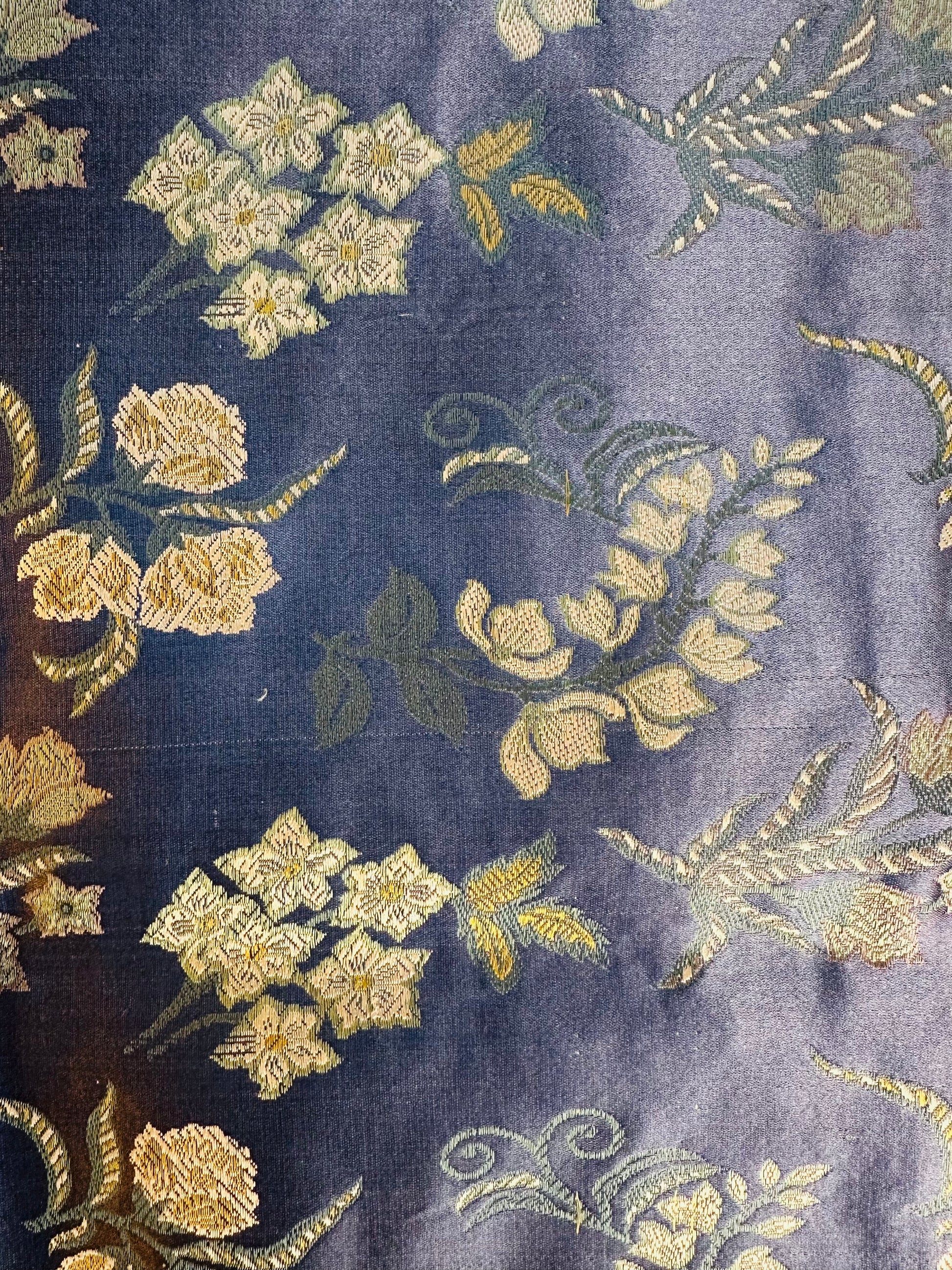 Macro view of the luminous Tanchoi weave where motifs are woven directly into slate blue silk.