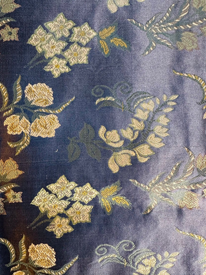 Macro view of the luminous Tanchoi weave where motifs are woven directly into slate blue silk.