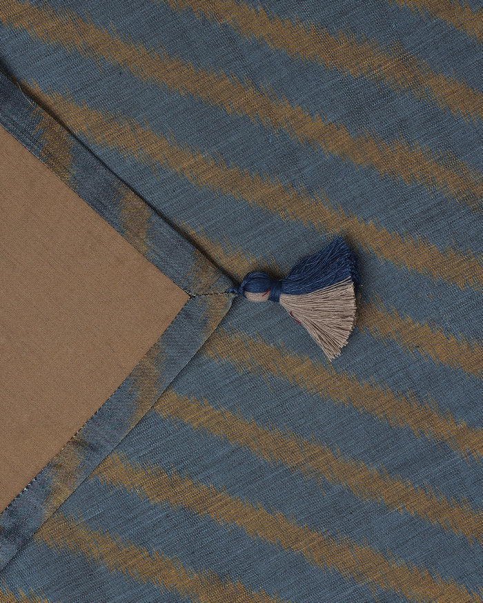 Close-up of the light blue and gold hand-loomed ikat stripes on the Tides ceremonial table silk.